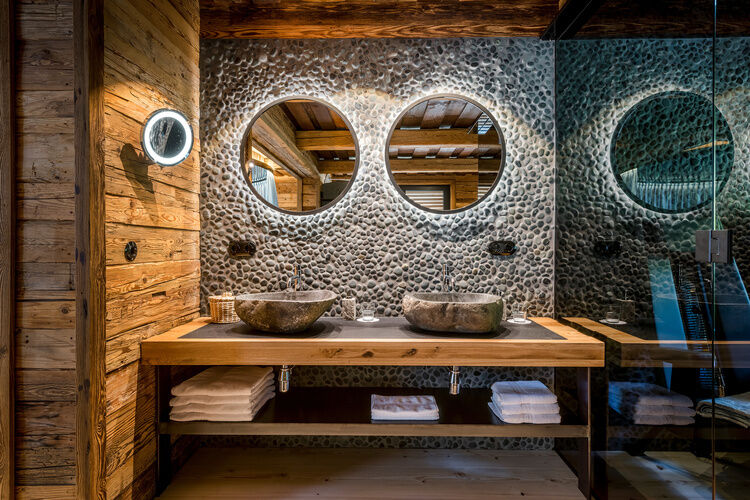 Badezimmer mit zwei Steinwaschbecken und runde Spiegel im Luxus Chalet Bayern