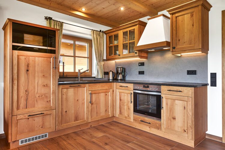 Eine Küche mit Holzmöbeln und schwarzen Arbeitsplatten im Chalet Wenighof.