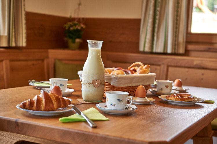 Ein Holztisch in Chalet Wenighof mit Tellern aus Keramik ist für das Frühstück gedeckt.