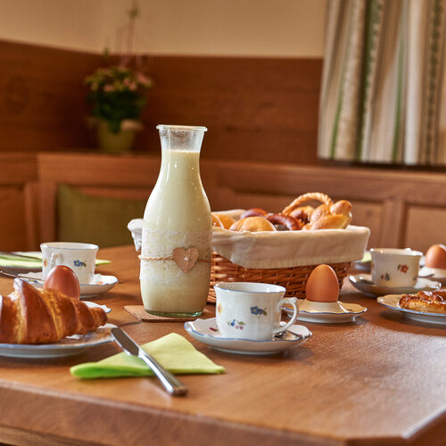 Ein Holztisch in Chalet Wenighof mit Tellern aus Keramik ist für das Frühstück gedeckt.