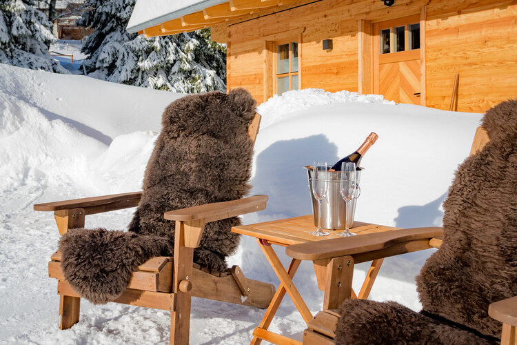Zwei Stühle mit flauschigen Decken und einer Champagnerflasche in der Mitte.