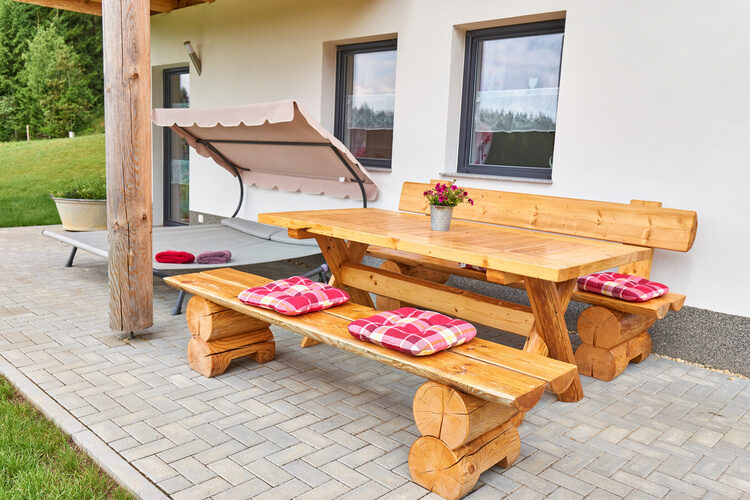Ein rustikaler Holztisch steht auf der Terrasse im Chalet Blumental.