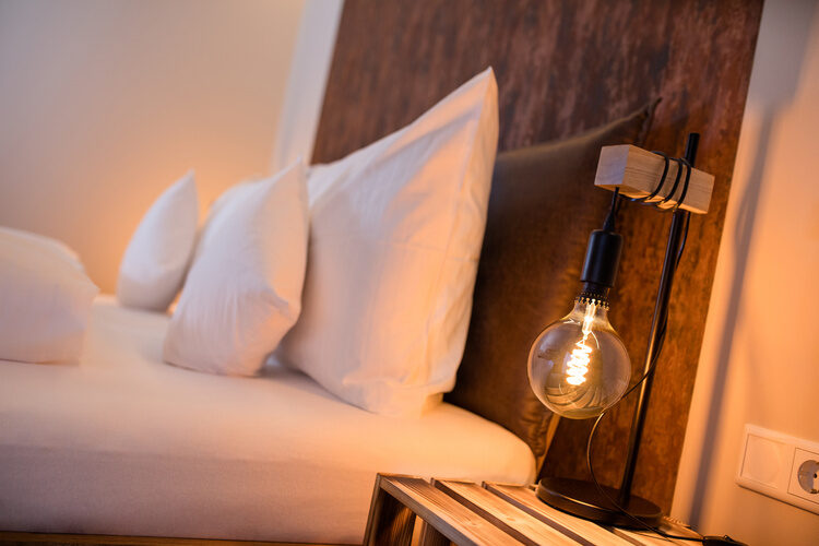 Das Bett mit weißer Bettwäsche und einer modernen Lampe im Chalet.
