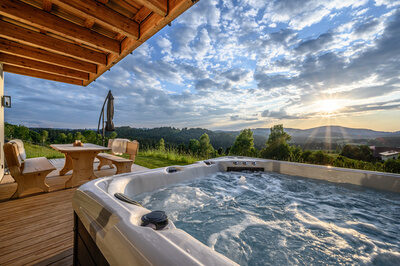 Ein Whirlpool auf dem Holzdeck des Kroner Chalets bei Abendd&auml;mmerung.