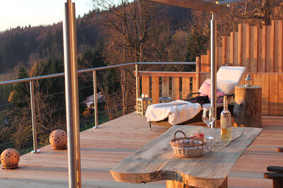 Ein Holzdeck mit einem Tisch und St&uuml;hlen in der Traumh&uuml;tte f&uuml;r Zwoa, einem Top Chalet im Bayerischen Wald.