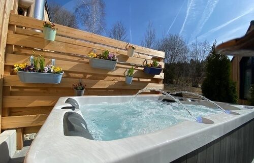 Ein Whirlpool steht vor einer Holzwand auf einer Chalet-Terrasse.