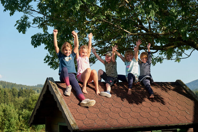 Fröhliche Kinder genießen ihre Ferien auf einem Dach.