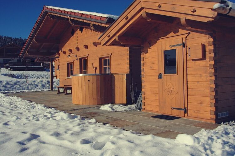 Ein gemütliches, verschneites Holzhaus mit weißem Dach im Bayerischen Wald.
