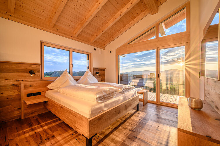 Ein großes Bett in einem Schlafzimmer des Kroner Chalets mit Holzwänden.