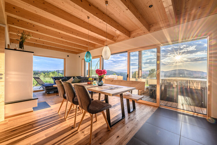 Der stilvolle Speiseraum mit Holzboden und großem Fenster im Kroner Chalet in Niederbayern.
