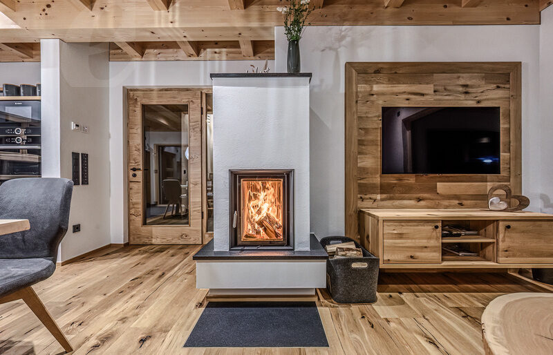 Ein geschmackvoll eingerichtetes Wohnzimmer im Kroner Chalets mit einem Kamin im Zentrum.