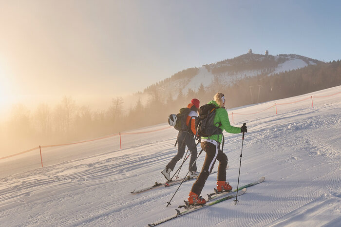 Zwei Personen steigen auf Skiern den Arber hinauf