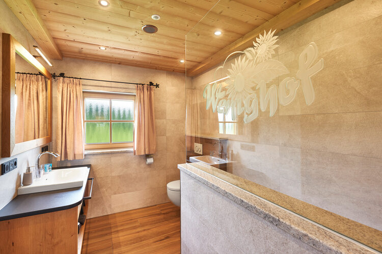 Ein geschmackvoll eingerichtetes Badezimmer mit Spiegel und Waschtisch im Chalet Wenighof.