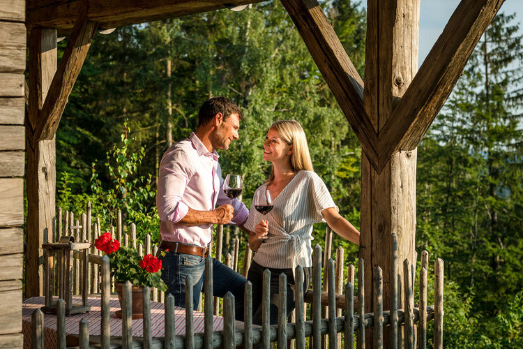 Pärchen auf der Luxus Chalet Bayern Terrasse sieht sich mit Weinglas in der Hand in die Augen