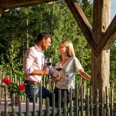 Pärchen auf der Luxus Chalet Bayern Terrasse sieht sich mit Weinglas in der Hand in die Augen