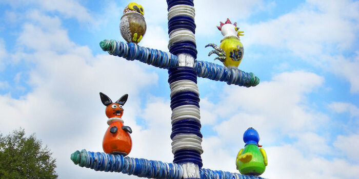 Auf einem Maibaum stehen Stofftiere