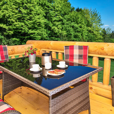 Ein Tisch und Stühle auf der Terrasse des Chalet Blumental vor einem baumbestandenen Hintergrund.