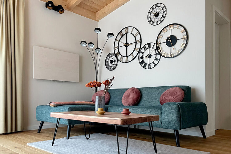 Ein stilvoll eingerichtetes Wohnzimmer im Im Waidlerland mit einem Sofa und einer Wand Uhr.