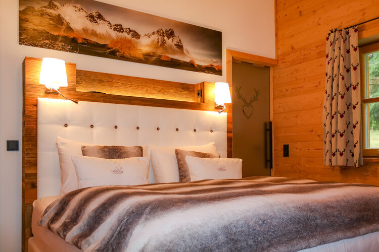 Ein stilvolles Bett im Schlafzimmer mit Blick auf das Fenster und den Bayerischen Wald.