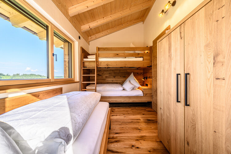 Ein rustikal gestaltetes Schlafzimmer in den Kroner Chalets mit Holzwänden und sommerlichen Ambiente.